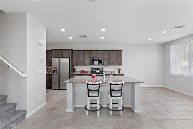 2276 Sky Island Dr, Henderson, NV 89002 - kitchen featuring appliances with stainless steel finishes, a kitchen island with sink, dark brown cabinets, recessed lighting, and light tile patterned flooring