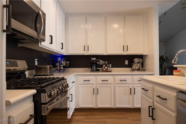 5400 Tassara Way Unit 106, Las Vegas, NV 89108 - kitchen with stainless steel appliances, white cabinetry, wood finished floors, light countertops, and a sink
