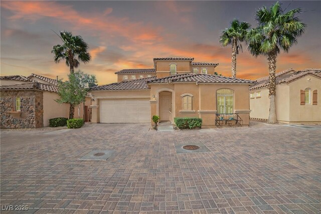 153 Via Di Mello, Henderson, NV 89011 - mediterranean / spanish-style house featuring stucco siding, decorative driveway, a tiled roof, and an attached garage