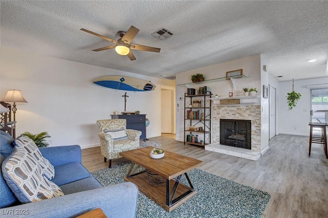 227 N Lamb Blvd Unit B, Las Vegas, NV 89110 - living area with a ceiling fan, a textured ceiling, a stone fireplace, wood finished floors, and baseboards