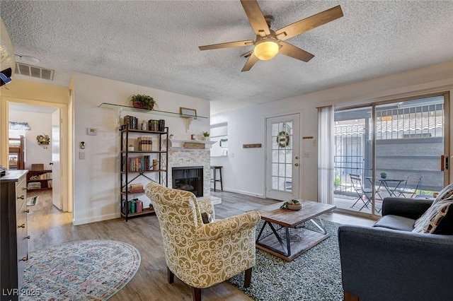 227 N Lamb Blvd Unit B, Las Vegas, NV 89110 - living area with a textured ceiling, wood finished floors, a ceiling fan, a glass covered fireplace, and baseboards