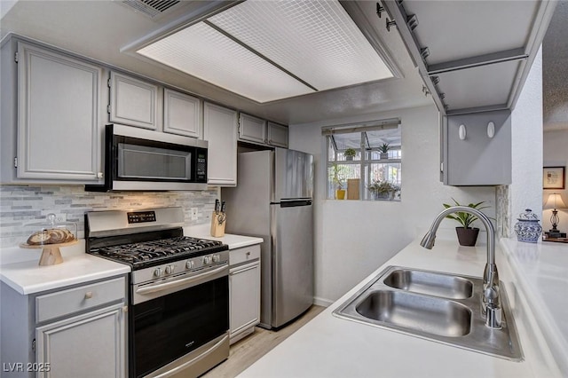 227 N Lamb Blvd Unit B, Las Vegas, NV 89110 - kitchen with appliances with stainless steel finishes, a sink, gray cabinets, decorative backsplash, and light countertops