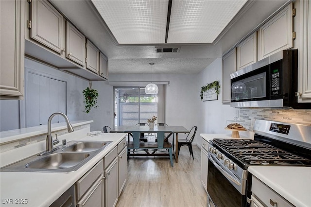 227 N Lamb Blvd Unit B, Las Vegas, NV 89110 - kitchen featuring appliances with stainless steel finishes, a sink, gray cabinetry, light wood-style floors, and light countertops