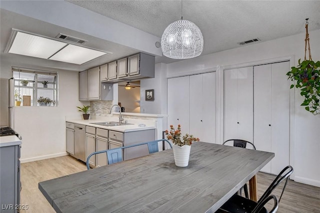 227 N Lamb Blvd Unit B, Las Vegas, NV 89110 - dining space with light wood-type flooring, a chandelier, ceiling fan, a textured ceiling, and baseboards