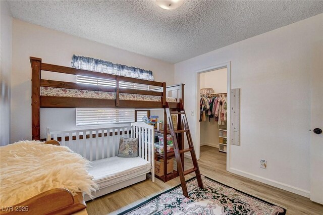 227 N Lamb Blvd Unit B, Las Vegas, NV 89110 - bedroom with wood finished floors, a walk in closet, a textured ceiling, baseboards, and a closet