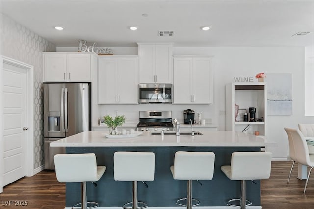 3729 Canis Minor Ln Unit 10206, Henderson, NV 89052 - kitchen featuring stainless steel appliances, a sink, wallpapered walls, dark wood-type flooring, and a kitchen bar