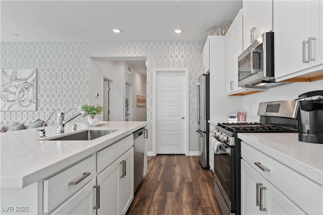 3729 Canis Minor Ln Unit 10206, Henderson, NV 89052 - kitchen with wallpapered walls, stainless steel appliances, a sink, dark wood finished floors, and white cabinetry
