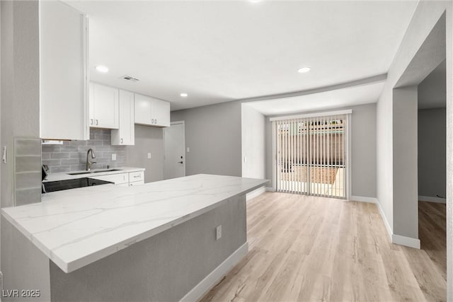 5817 Glen Eagles Ln, Las Vegas, NV 89108 - kitchen featuring light wood-style floors, white cabinetry, light stone counters, a sink, and baseboards