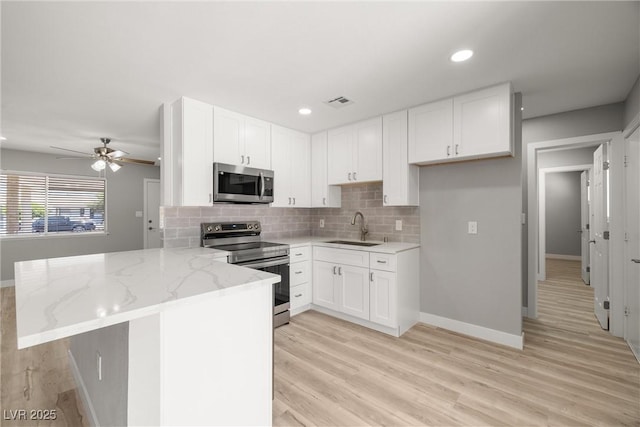 5817 Glen Eagles Ln, Las Vegas, NV 89108 - kitchen with appliances with stainless steel finishes, a sink, a peninsula, light stone counters, and tasteful backsplash