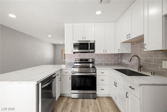 5817 Glen Eagles Ln, Las Vegas, NV 89108 - kitchen featuring appliances with stainless steel finishes, a sink, a peninsula, light stone counters, and decorative backsplash