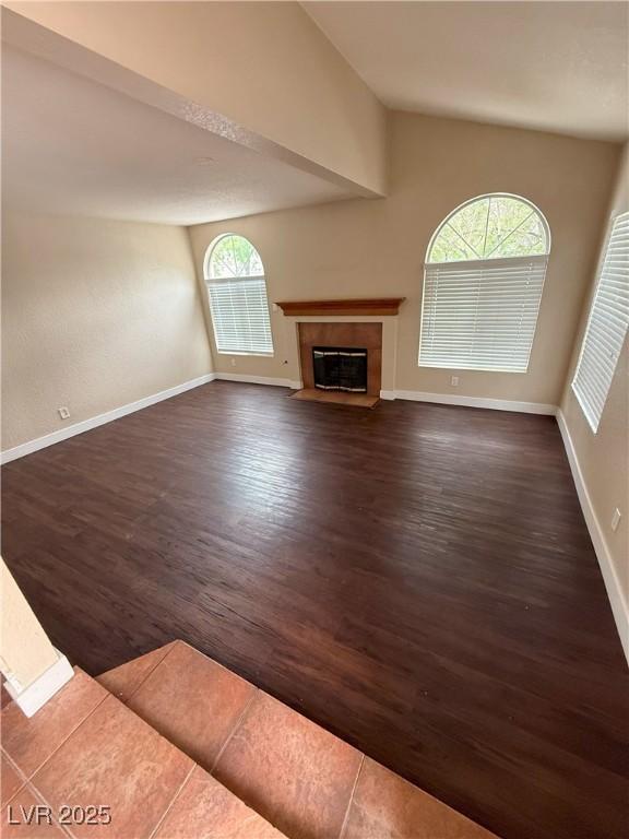 7969 Cina Ave, Las Vegas, NV 89147 - unfurnished living room with lofted ceiling, dark wood finished floors, a fireplace with flush hearth, and baseboards
