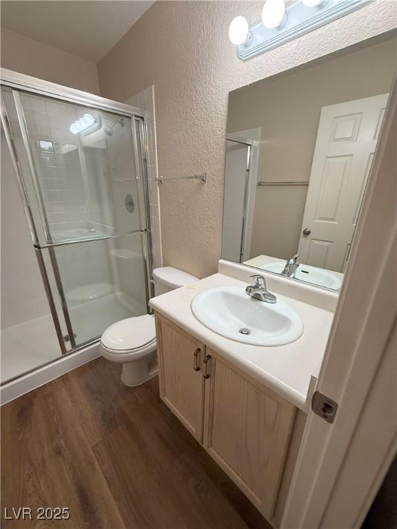 7969 Cina Ave, Las Vegas, NV 89147 - bathroom with a textured wall, wood finished floors, toilet, a stall shower, and vanity