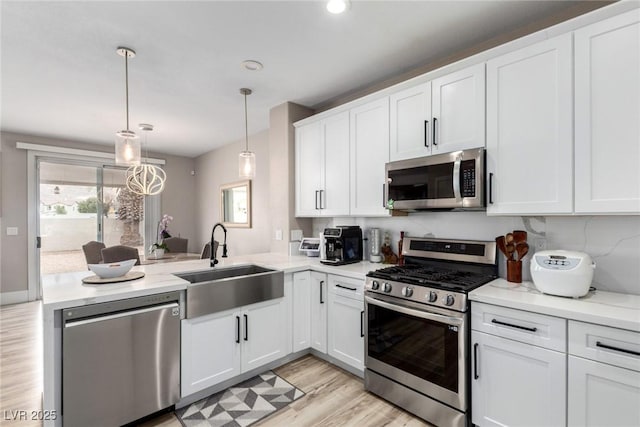 1360 Angel Falls St, Las Vegas, NV 89142 - kitchen with appliances with stainless steel finishes, a sink, a peninsula, white cabinets, and light wood-type flooring