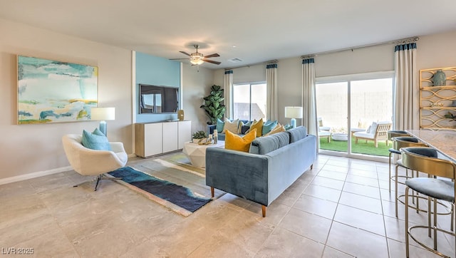 living area with a ceiling fan, baseboards, and light tile patterned flooring