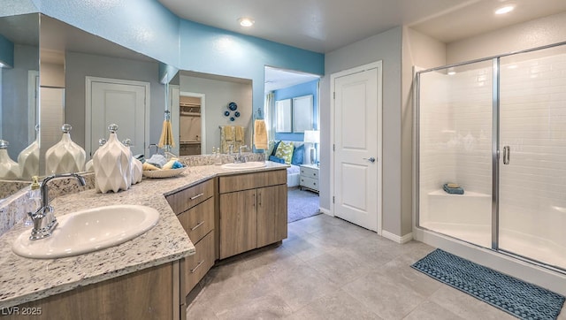 bathroom featuring a stall shower, double vanity, baseboards, recessed lighting, and a walk in closet