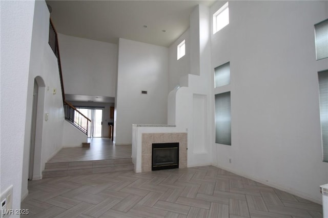 3440 Crystal Tower St, Las Vegas, NV 89129 - unfurnished living room with a towering ceiling, stairway, a fireplace, and arched walkways