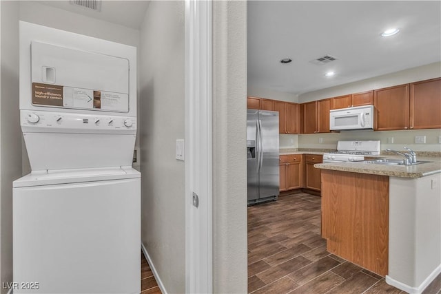 7632 Calico Fields St, Las Vegas, NV 89149 - kitchen featuring white appliances, stacked washing machine and dryer, dark wood finished floors, a sink, and recessed lighting
