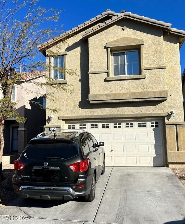 view of front of property featuring an attached garage, stucco siding, driveway, and a tile roof