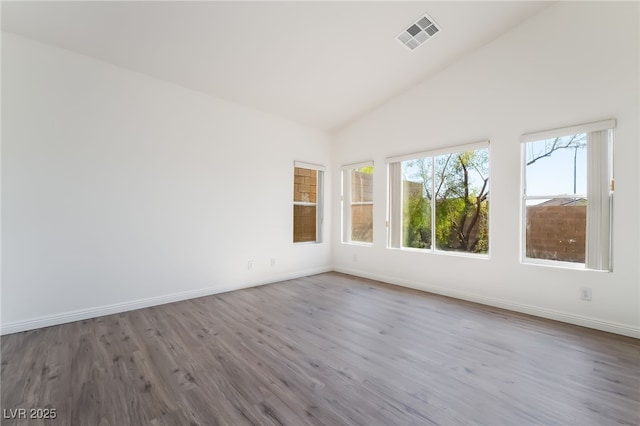 empty room with wood finished floors, baseboards, and high vaulted ceiling