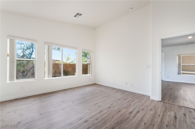 spare room featuring wood finished floors, healthy amount of natural light, and baseboards