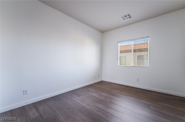 empty room featuring dark wood-type flooring and baseboards