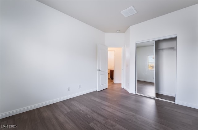 unfurnished bedroom featuring dark wood-style flooring, a closet, and baseboards