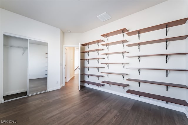 unfurnished bedroom featuring wood finished floors, baseboards, and a closet