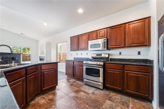 kitchen with stainless steel appliances, vaulted ceiling, a sink, dark countertops, and recessed lighting