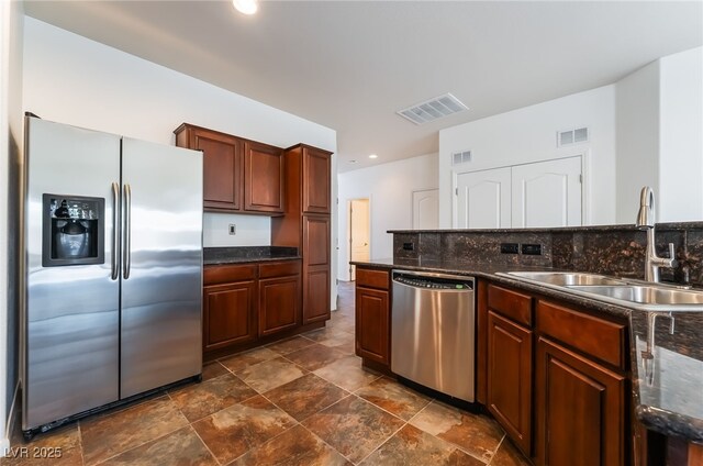 kitchen featuring appliances with stainless steel finishes, a sink, dark stone finish flooring, backsplash, and recessed lighting