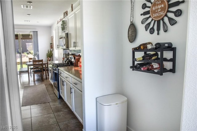 5733 Coral Sun St, North Las Vegas, NV 89031 - kitchen featuring stainless steel appliances, white cabinets, dark tile patterned flooring, and decorative backsplash