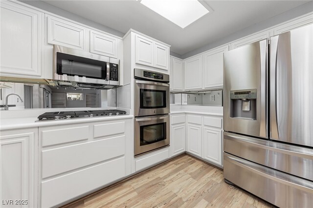 9917 Arbuckle Dr, Las Vegas, NV 89134 - kitchen featuring stainless steel appliances, light countertops, white cabinets, and light wood-style floors