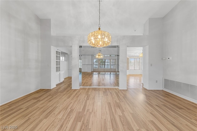 9917 Arbuckle Dr, Las Vegas, NV 89134 - unfurnished room featuring a chandelier, a towering ceiling, light wood-style floors, and baseboards