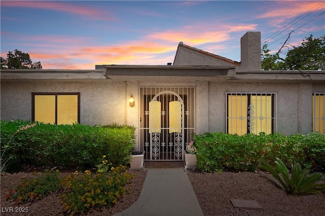 2479 Domingo St, Las Vegas, NV 89121 - doorway to property featuring stucco siding and a chimney