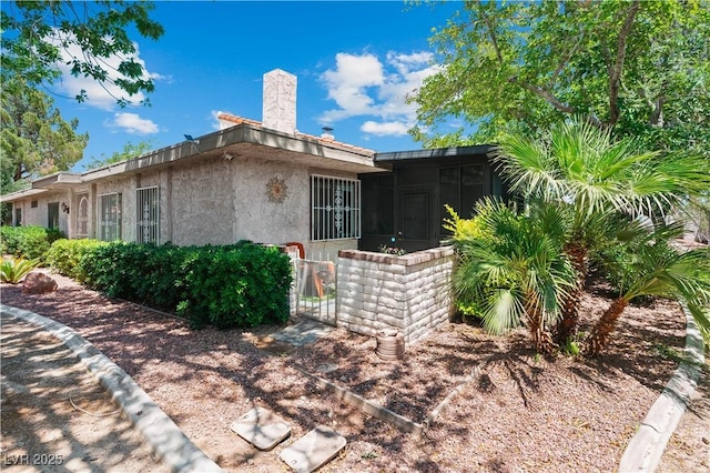2479 Domingo St, Las Vegas, NV 89121 - view of property exterior with stucco siding, a sunroom, a chimney, and a gate