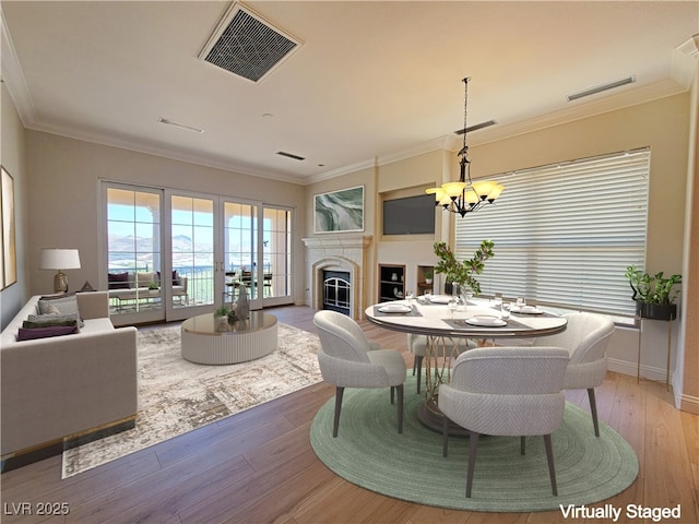 dining room with a chandelier, a fireplace, light wood finished floors, crown molding, and baseboards
