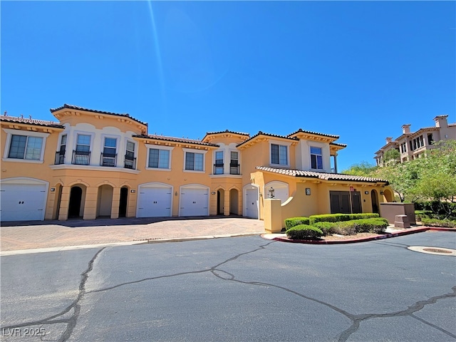 mediterranean / spanish-style house featuring an attached garage, stucco siding, driveway, and a tiled roof