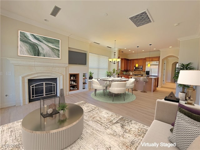 living area featuring light wood-style flooring, recessed lighting, a glass covered fireplace, arched walkways, and baseboards