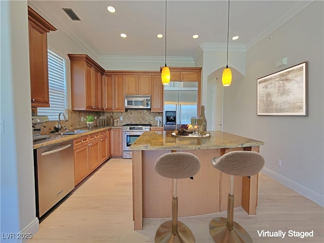 kitchen featuring appliances with stainless steel finishes, a sink, light wood-style flooring, ornamental molding, and tasteful backsplash
