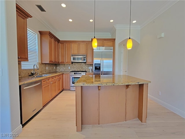kitchen featuring appliances with stainless steel finishes, a sink, crown molding, a center island, and tasteful backsplash
