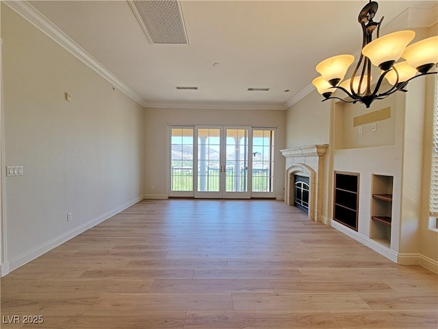 unfurnished living room with a chandelier, light wood finished floors, crown molding, baseboards, and built in features