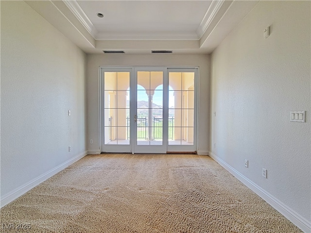 unfurnished room featuring crown molding, light carpet, a tray ceiling, baseboards, and a textured wall