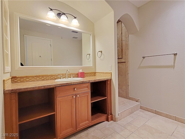 bathroom featuring vanity, baseboards, a tile shower, and tile patterned floors