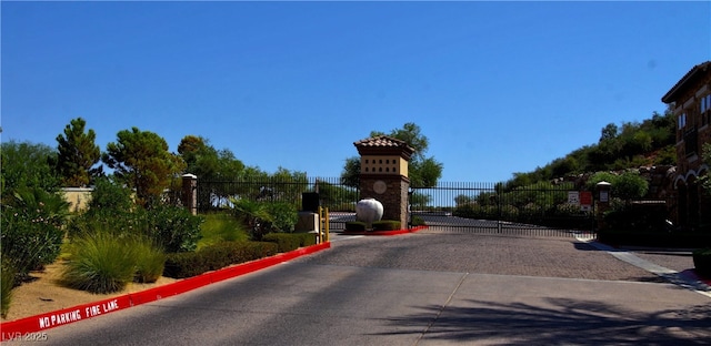 view of street with curbs, a gate, and a gated entry