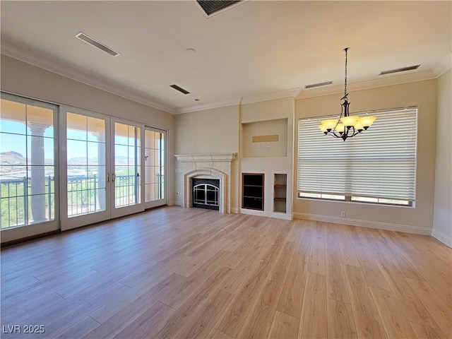 unfurnished living room featuring a chandelier, light wood-style flooring, ornamental molding, baseboards, and a fireplace