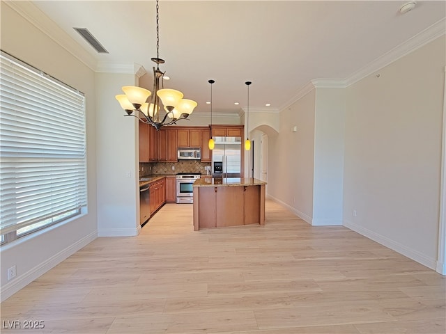 kitchen featuring appliances with stainless steel finishes, a chandelier, arched walkways, light wood finished floors, and ornamental molding