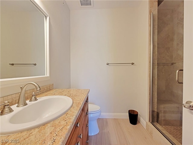 full bath featuring a stall shower, wood finished floors, toilet, vanity, and tasteful backsplash