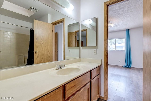 875 Rhinegold Way, Las Vegas, NV 89110 - bathroom with vanity, a textured ceiling, a shower with shower curtain, wood finished floors, and baseboards