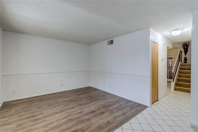 875 Rhinegold Way, Las Vegas, NV 89110 - empty room with a textured ceiling, stairs, light wood-style floors, and baseboards