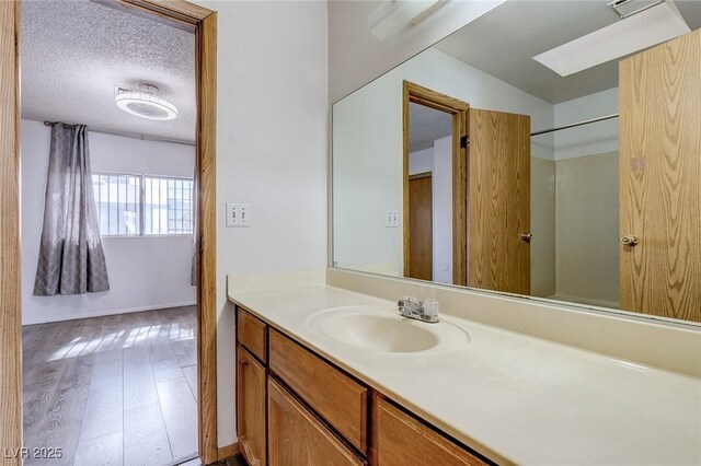 875 Rhinegold Way, Las Vegas, NV 89110 - bathroom with vanity, a skylight, wood finished floors, a textured ceiling, and baseboards