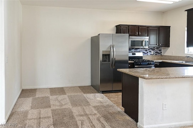 5650 E Sahara Ave Unit 2062, Las Vegas, NV 89142 - kitchen featuring stainless steel appliances, a sink, dark brown cabinetry, light colored carpet, and tasteful backsplash